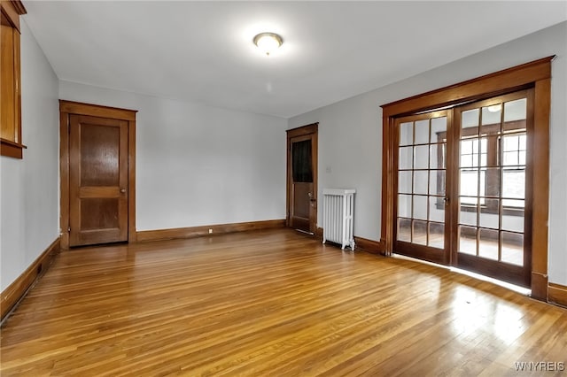 spare room with light wood-type flooring, baseboards, and radiator heating unit