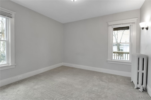 empty room with baseboards, carpet floors, and radiator heating unit