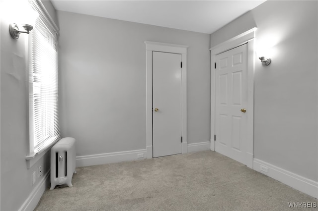 unfurnished bedroom featuring radiator, baseboards, and carpet floors