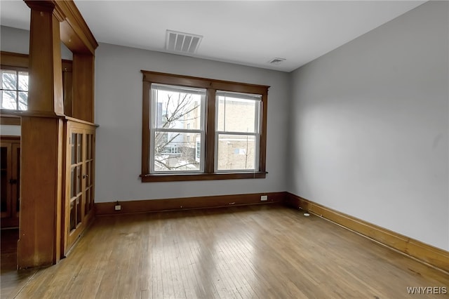 unfurnished room featuring a wealth of natural light, visible vents, and light wood-style floors