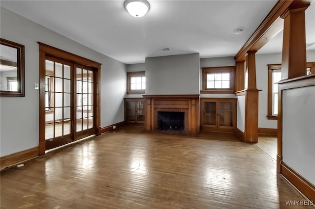 unfurnished living room with baseboards, hardwood / wood-style floors, and a fireplace