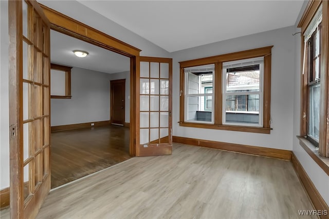 spare room with lofted ceiling, wood finished floors, and baseboards