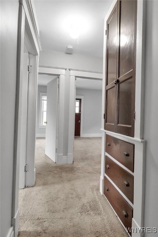 hallway with light colored carpet and baseboards