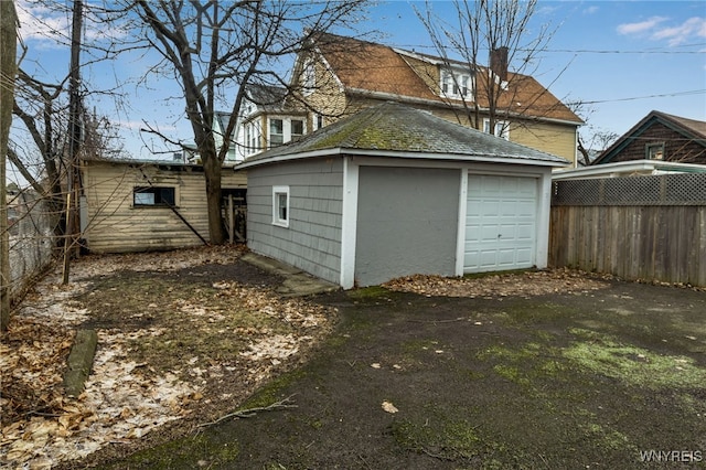 detached garage featuring driveway and fence