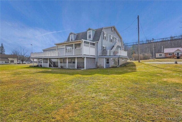 rear view of house with a yard, a gambrel roof, and a sunroom