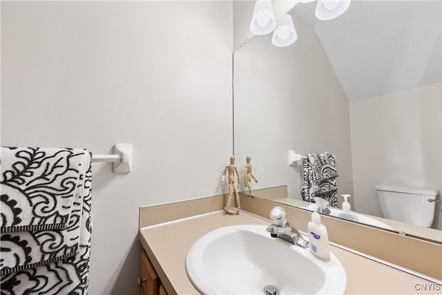 bathroom featuring vanity, lofted ceiling, and toilet