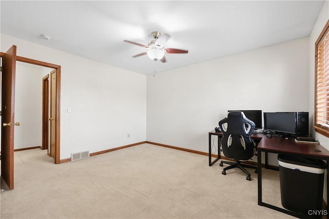 office area with visible vents, light carpet, baseboards, and a ceiling fan