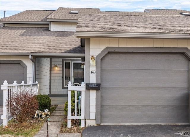 view of front of house featuring aphalt driveway, an attached garage, and a shingled roof