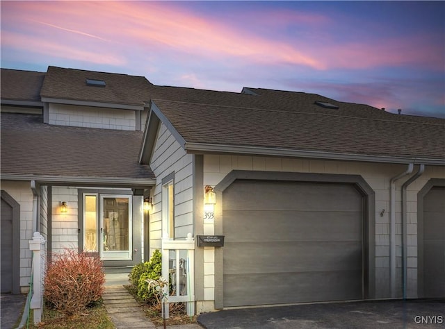 view of front of property featuring a garage, driveway, and a shingled roof