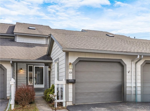 townhome / multi-family property with a garage, driveway, and a shingled roof