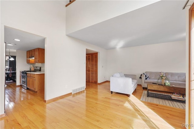 living area with light wood-type flooring, visible vents, and baseboards