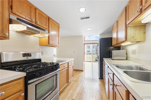 kitchen featuring visible vents, under cabinet range hood, a sink, light countertops, and stainless steel range with gas stovetop