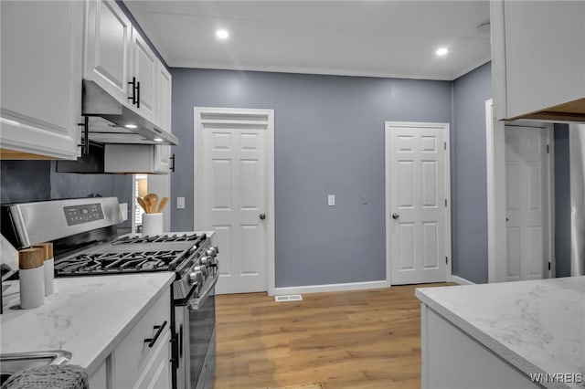 kitchen with light stone countertops, under cabinet range hood, gas range, light wood-style flooring, and white cabinets