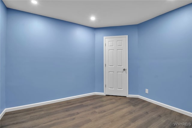 empty room with dark wood finished floors, recessed lighting, and baseboards