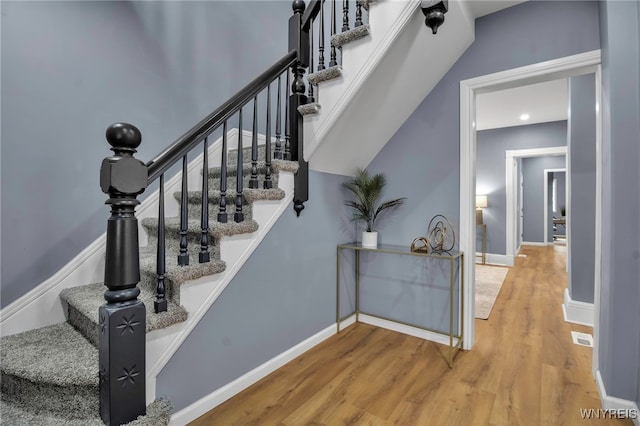 staircase featuring visible vents, baseboards, and wood finished floors