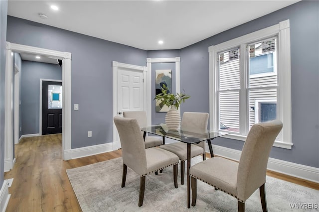 dining area with light wood-style flooring, a healthy amount of sunlight, and baseboards