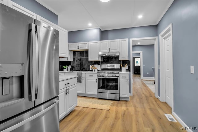 kitchen featuring visible vents, light countertops, under cabinet range hood, appliances with stainless steel finishes, and backsplash