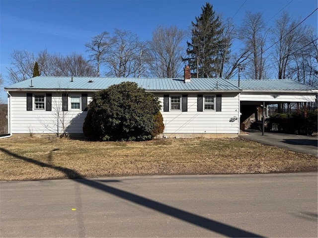 single story home featuring an attached carport, concrete driveway, a chimney, and metal roof