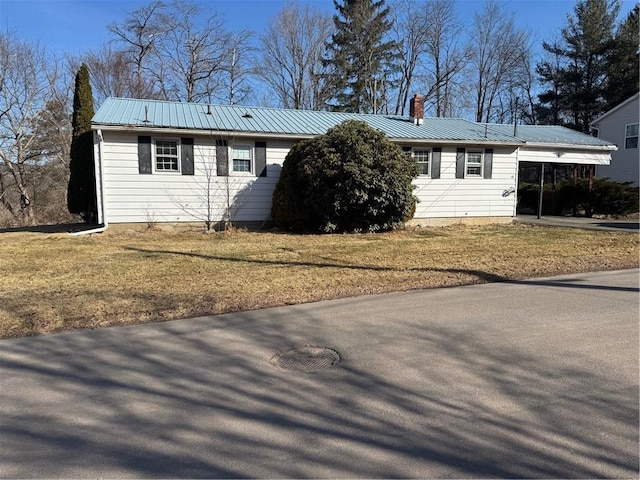 single story home with metal roof, driveway, an attached carport, and a chimney