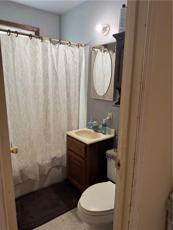 bathroom featuring vanity, toilet, shower / tub combo, and tile patterned flooring