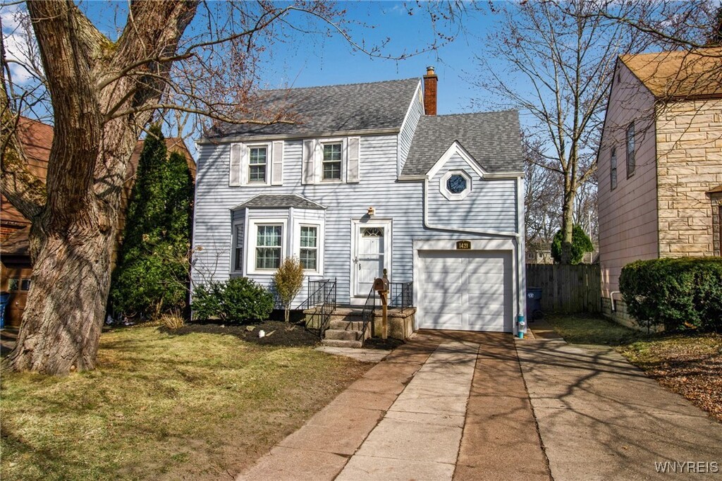 view of front of property with fence, concrete driveway, roof with shingles, a chimney, and an attached garage
