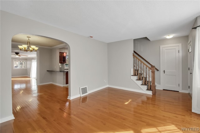 unfurnished room with stairway, baseboards, arched walkways, and light wood finished floors