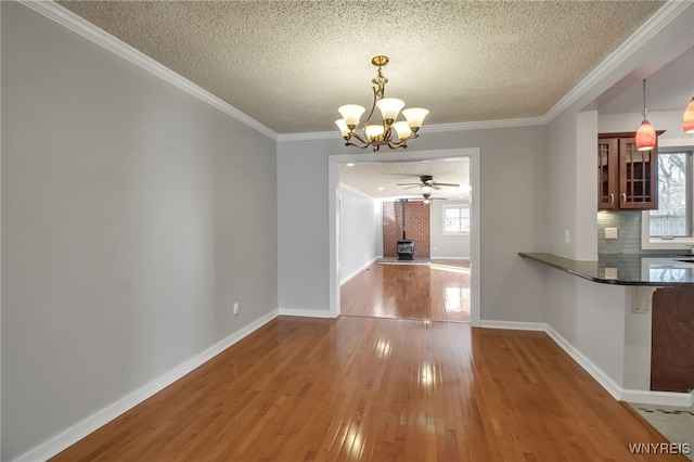 unfurnished dining area with a wealth of natural light, ornamental molding, a wood stove, and wood-type flooring