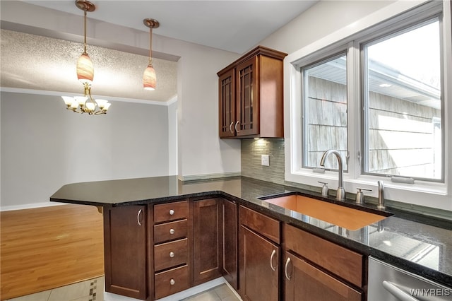 kitchen with dark stone counters, a sink, a textured ceiling, dishwasher, and a chandelier