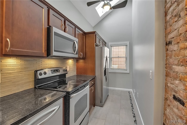 kitchen with a ceiling fan, baseboards, appliances with stainless steel finishes, lofted ceiling with skylight, and backsplash