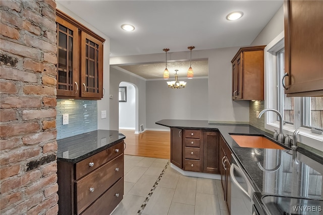 kitchen featuring a notable chandelier, a sink, dark stone countertops, arched walkways, and a peninsula