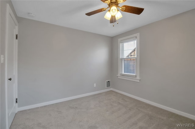 spare room with a ceiling fan, baseboards, visible vents, and light carpet