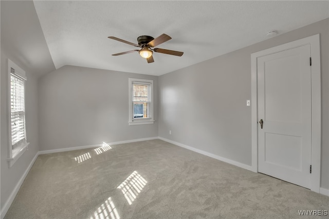 spare room with carpet floors, a healthy amount of sunlight, ceiling fan, and vaulted ceiling