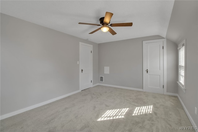 unfurnished bedroom featuring a ceiling fan, baseboards, visible vents, carpet floors, and vaulted ceiling