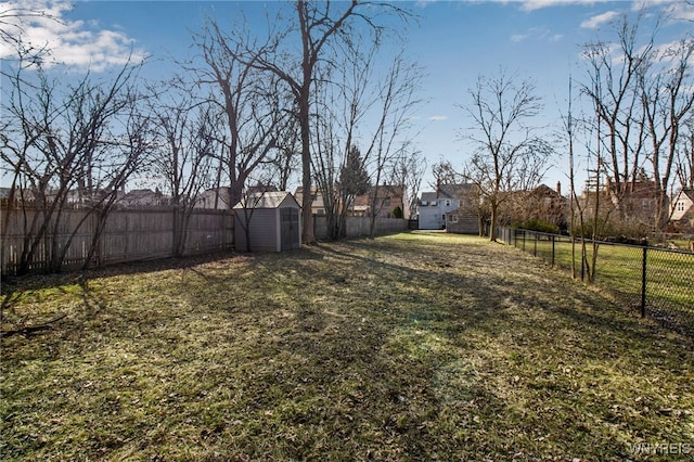 view of yard with a storage shed, an outbuilding, and a fenced backyard