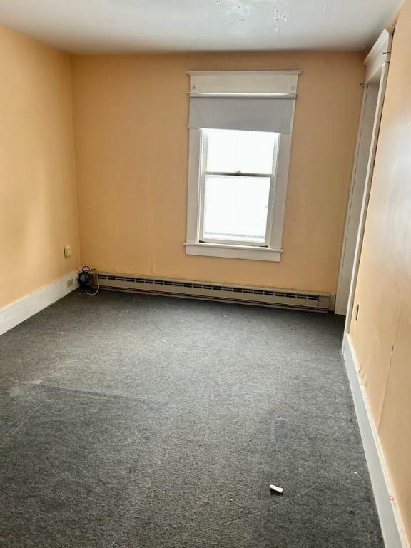 carpeted empty room featuring baseboards and a baseboard radiator