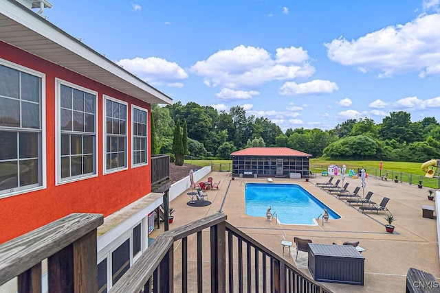 community pool featuring an outbuilding, a patio, and fence