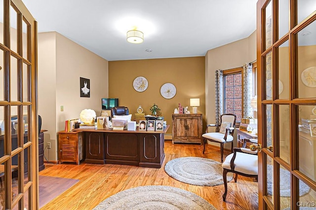 home office featuring french doors, baseboards, light wood-style floors, and baseboard heating