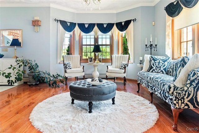 living area with crown molding, a notable chandelier, wood finished floors, and baseboard heating