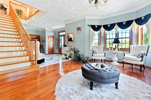 sitting room with baseboards, stairs, ornamental molding, wood finished floors, and a notable chandelier