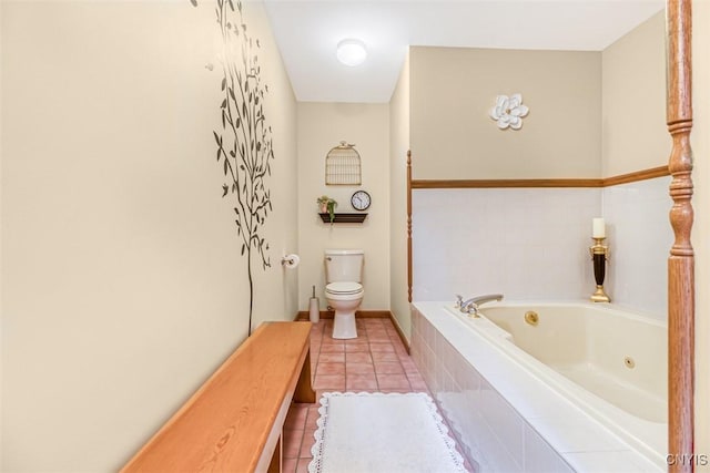 bathroom featuring tile patterned flooring, toilet, baseboards, and a whirlpool tub