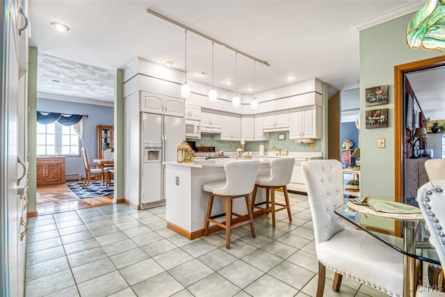 kitchen featuring crown molding, light countertops, a kitchen breakfast bar, white appliances, and white cabinetry