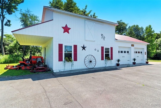 exterior space with aphalt driveway, metal roof, and a garage