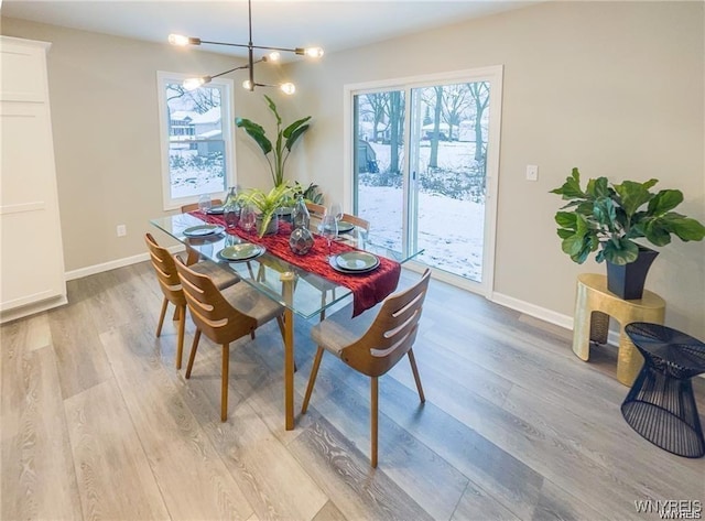 dining area featuring light wood finished floors, baseboards, and an inviting chandelier
