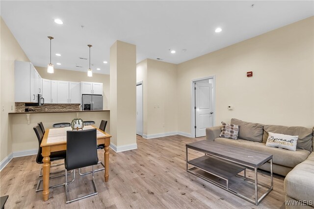 dining room with recessed lighting, light wood-type flooring, and baseboards