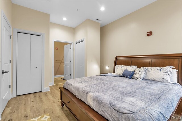 bedroom featuring visible vents, baseboards, recessed lighting, light wood-style floors, and two closets