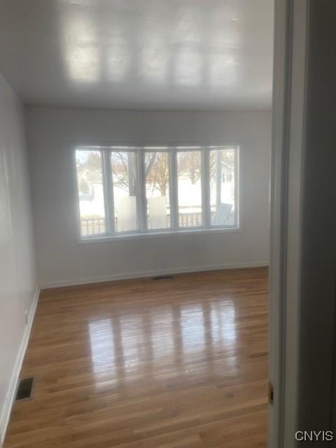 spare room with visible vents, baseboards, and wood finished floors