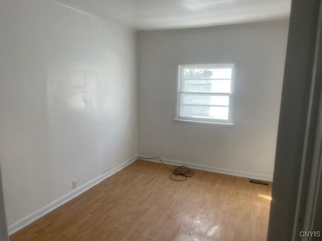 empty room featuring light wood-type flooring, baseboards, and visible vents