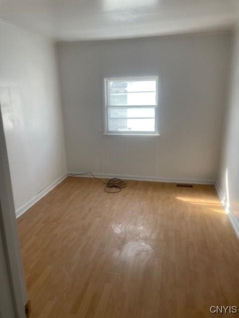 spare room with baseboards and light wood-style floors