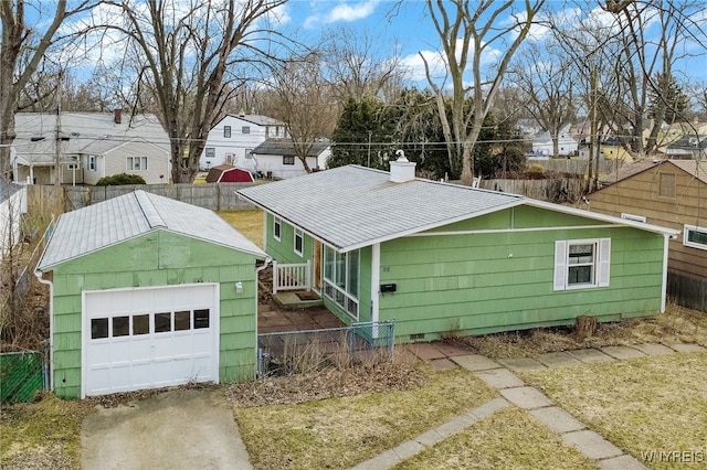 exterior space featuring a garage, a residential view, an outbuilding, and fence