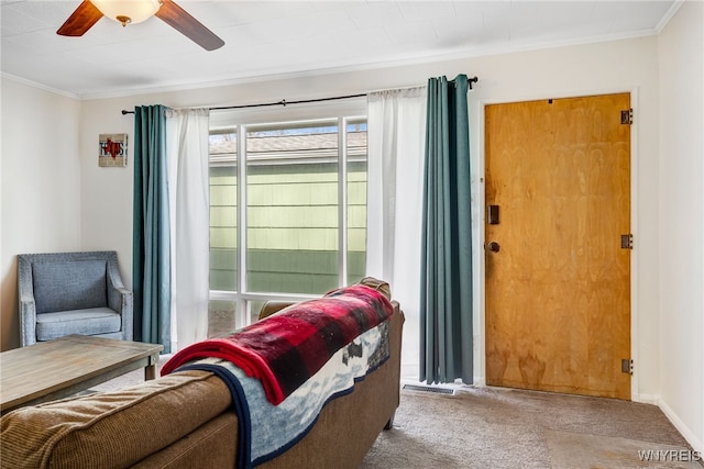 sitting room with visible vents, carpet floors, a ceiling fan, and crown molding